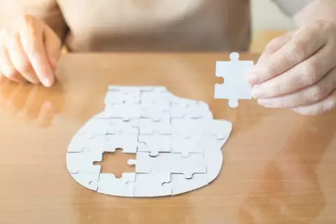 Puzzel van een hoofd met nog 1 puzzelstuk dat gelegd moet worden