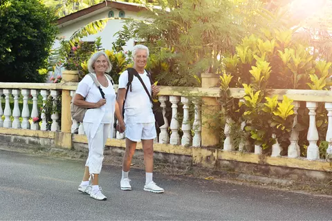 Een oudere man en vrouw in witte kledij die aan het wandelen zijn